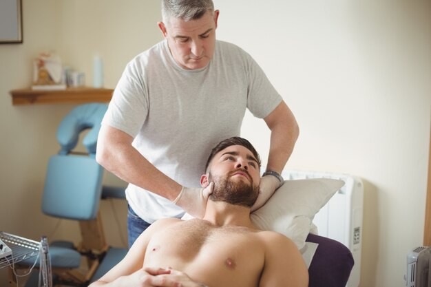 Physiotherapist examining neck of a patient