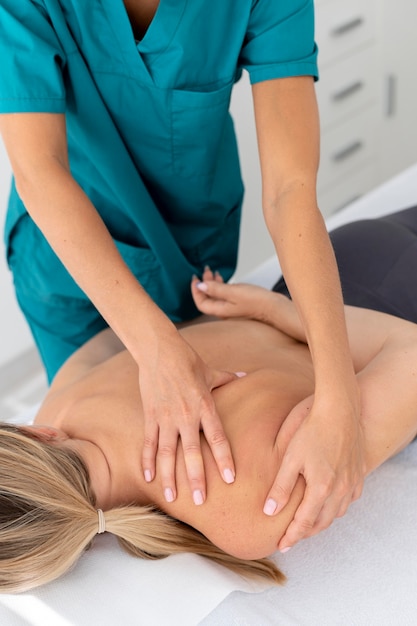 Физиотерапевт делает массаж своему пациенту в клинике