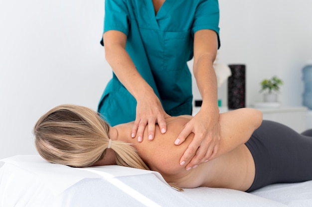 Физиотерапевт делает массаж своему пациенту