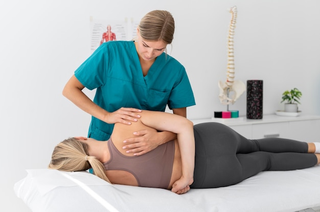 Free photo physiotherapist helping a patient at her clinic