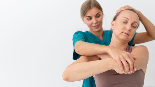 Free photo physiotherapist helping a patient at her clinic