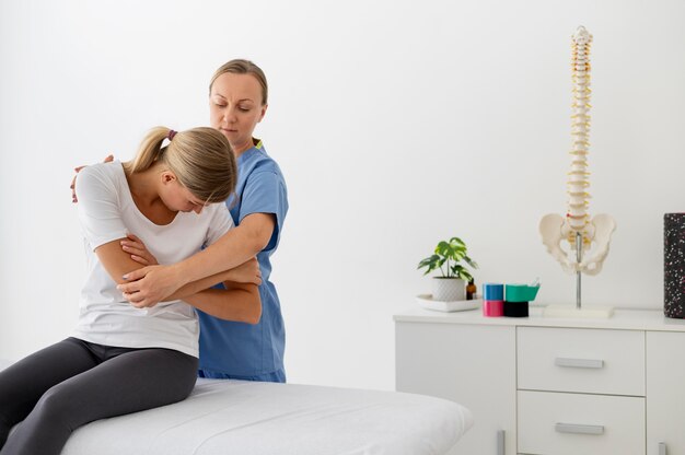 Free photo physiotherapist helping a young female patient at her clinic