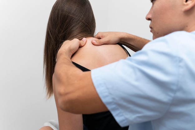 Physiotherapist massaging female patient's upper back