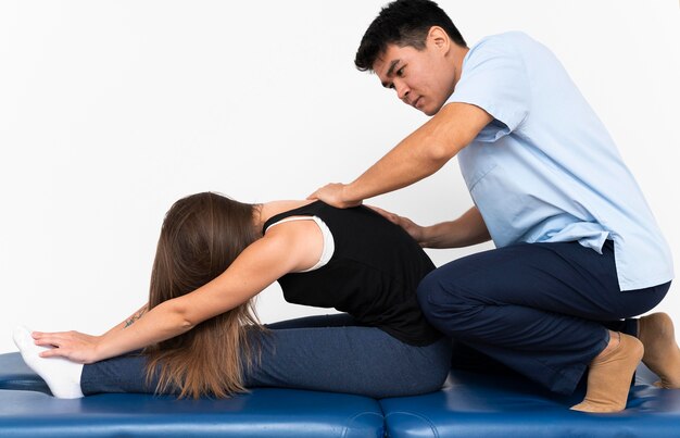 Физиотерапевт массирует верхнюю часть спины женщины от боли