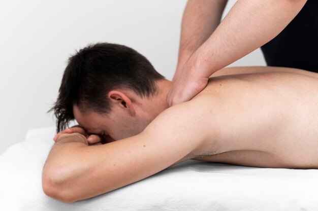 Physiotherapist performing back massage for male patient