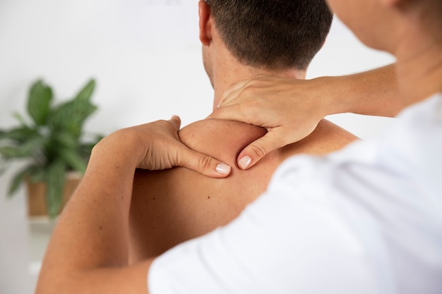 Foto gratuita fisioterapista che esegue massaggio terapeutico sul cliente maschio