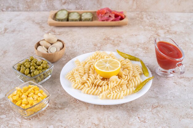 Pickle tray, vegetable bowls, ketchup glass and macaroni platter on marble surface.