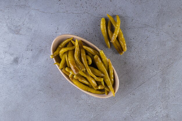 Pickled chili pepper placed on a stone surface.