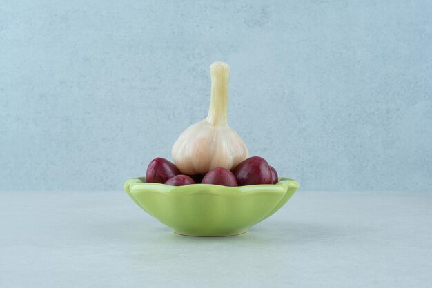 Pickled cornel cherries in bowl with fresh garlic.