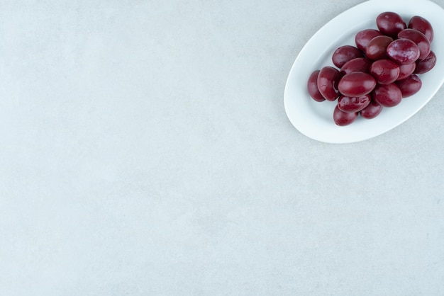 Pickled cornel cherries on white plate.