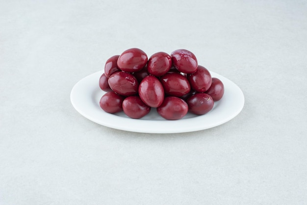 Pickled cornel cherries on white plate.