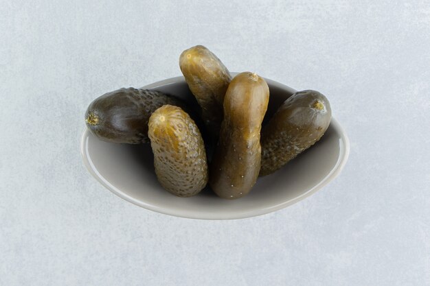 Pickled cucumber in the bowl, on the marble surface