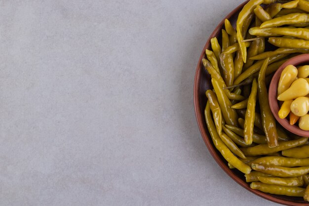 Pickled cucumbers in bowls placed on stone background.