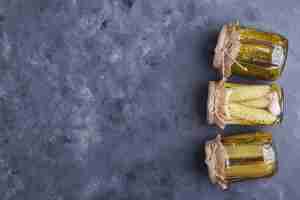 Free photo pickled cucumbers in glass jars on blue background.