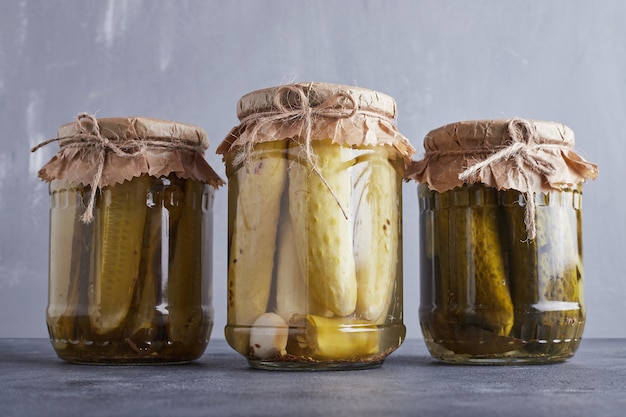 Pickled cucumbers in glass jars on blue wall.