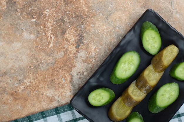 Pickled and fresh cucumber slices on black plate