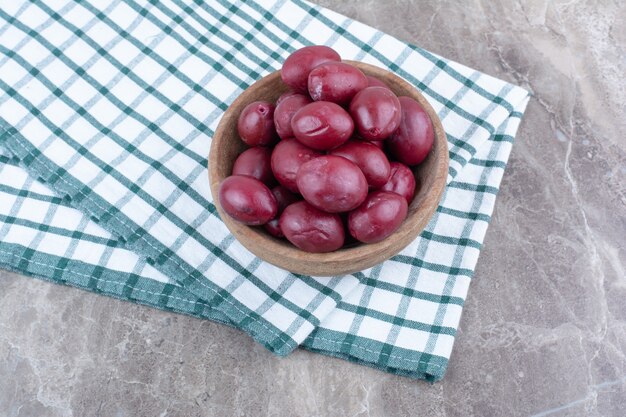 Pickled fruits in wooden bowl with tablecloth.