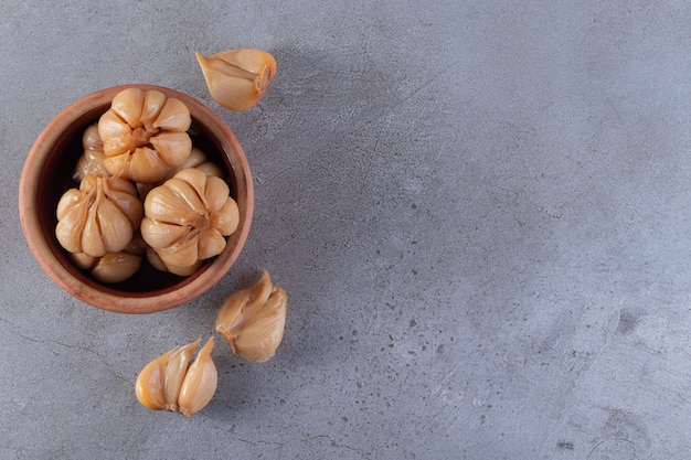 Pickled garlic placed on a stone background.