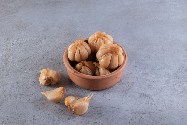 Pickled garlic placed on a stone surface.