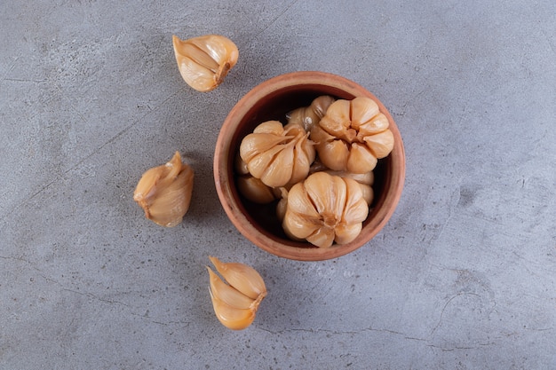 Pickled garlic placed on a stone surface.