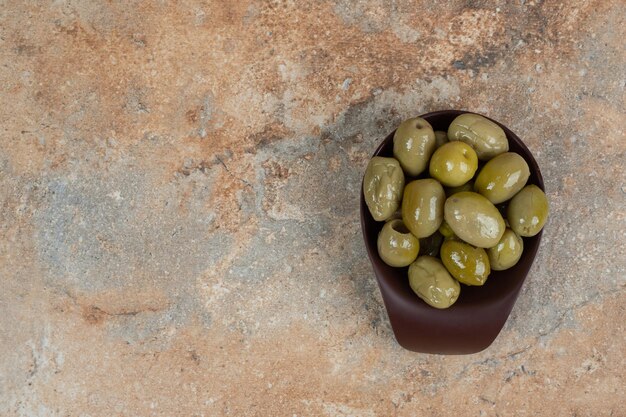 Free photo pickled green olives in dark bowl