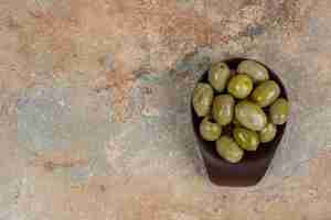 Бесплатное фото Маринованные зеленые оливки в темной миске