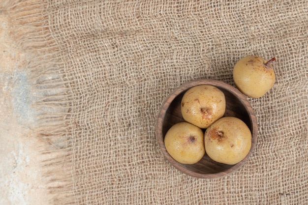 Pickled green plums in wooden bowl