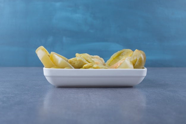 Free photo pickled green tomato on white plate over grey.