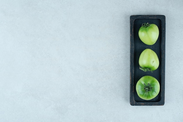 Free photo pickled green tomatoes on black plate.