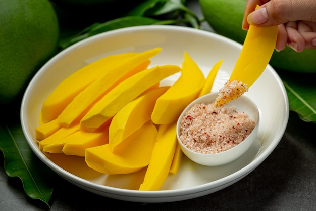 Pickled mango on dark wooden surface