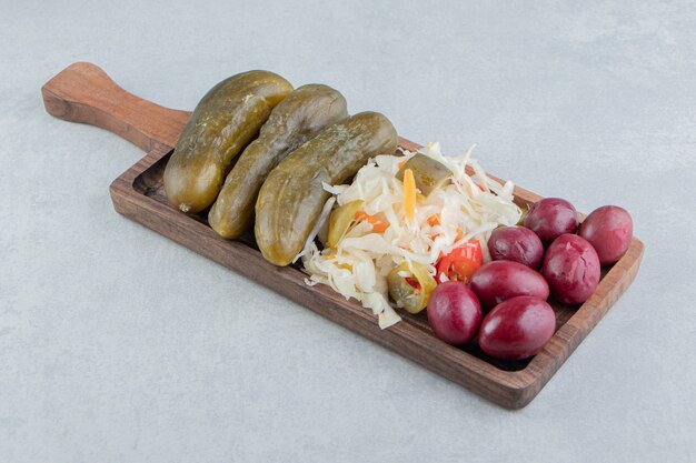 Pickled olive, cabbage and cucumber on a board on the marble surface