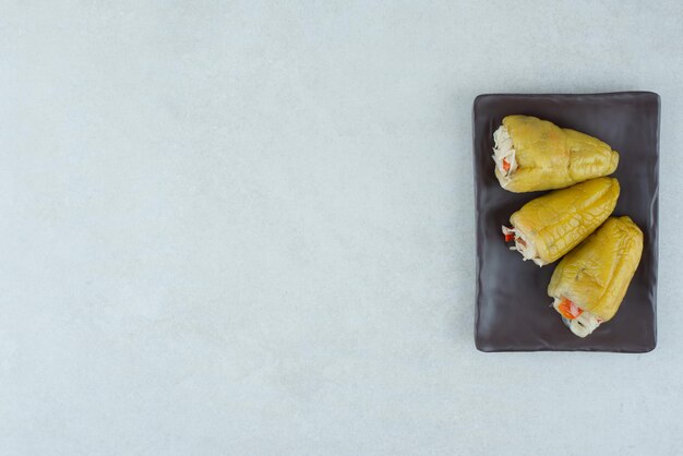 Free photo pickled peppers stuffed with vegetables on black plate.