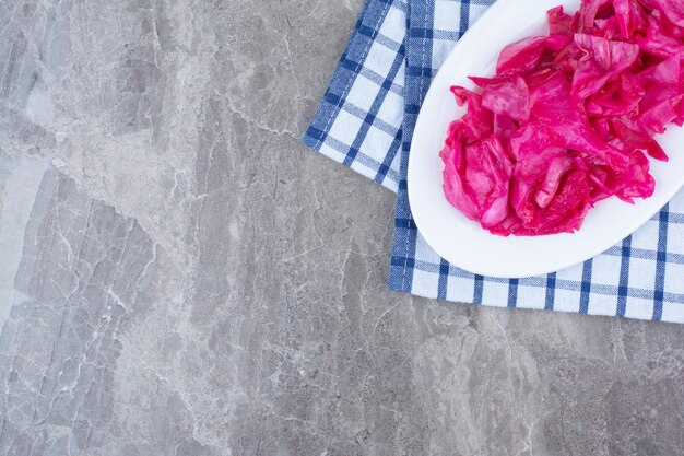 Pickled red cabbage on white plate with tablecloth.