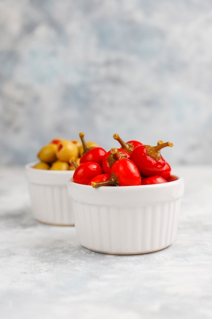 Pickled small round red hot cherry chili peppers on grey concrete 