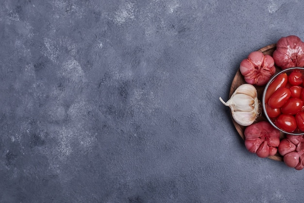 Free photo pickled tomatoes and garlic on wooden plate.