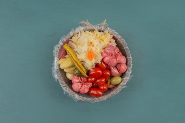 Pickled tomatoes, olives, garlic, cabbage, cucumbers in wooden bucket. 