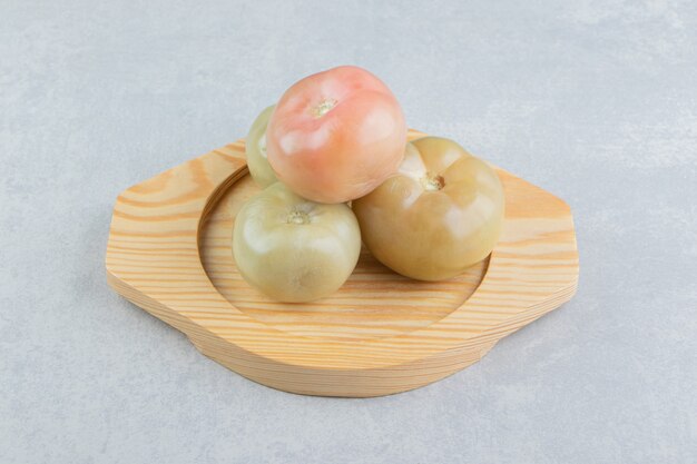 Маринованные помидоры на деревянной тарелке