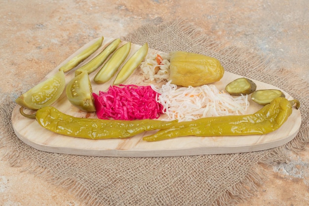 Pickled vegetables and sauerkraut on wooden board