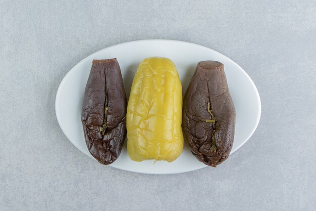 Pickles pepper and eggplants on a plate on the marble surface