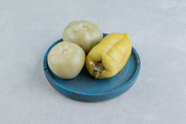 Бесплатное фото Соленые помидоры и сладкий перец на деревянной тарелке, на мраморной поверхности