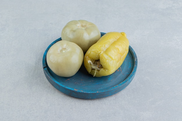 Free photo pickles tomatoes and sweet pepper on a wooden plate, on the marble surface