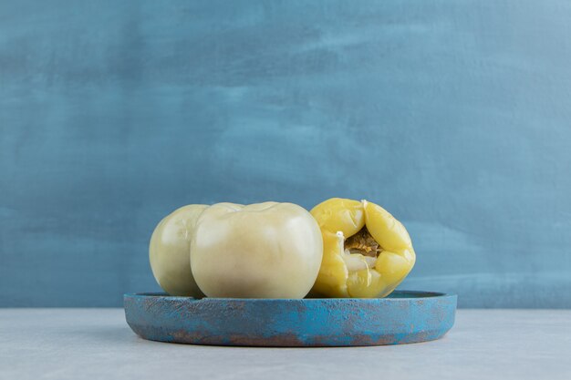 Pickles tomatoes and sweet pepper on a wooden plate   