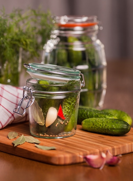 Pickles with garlic in glass jar on cutting board