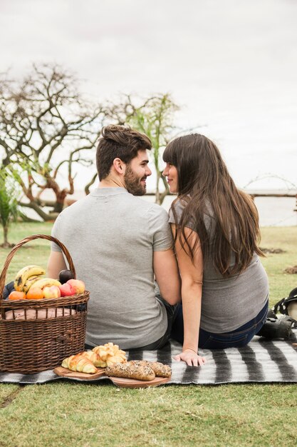 Picnic basket and baked bread in front of young couple looking at each other