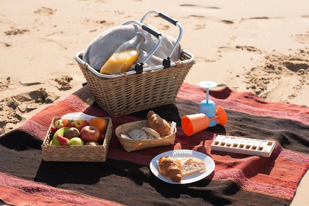 Picnic basket on blanket on beach. Basket, food and drinks on blanket on seashore. Picnic, food, relaxation concept