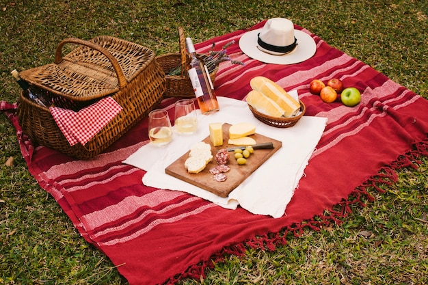 Picnic basket with goodies on red blanket 