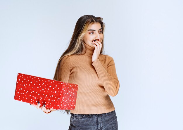 Picture of an attractive woman model holding a red present.