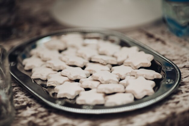 Free photo picture of a big silver plate with a lot of white star cookies on the table