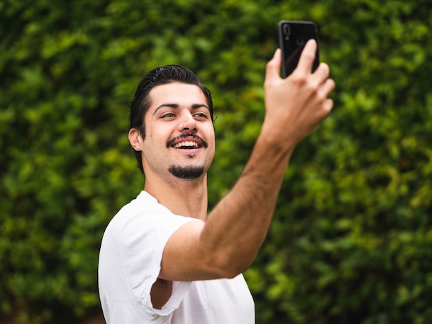 緑に対してselfiesを取っているブルネットの男性の写真