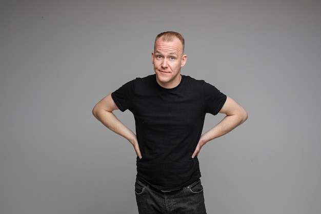 Picture of caucasian male wearing a t-shirt and jeans isolated over the grey wall